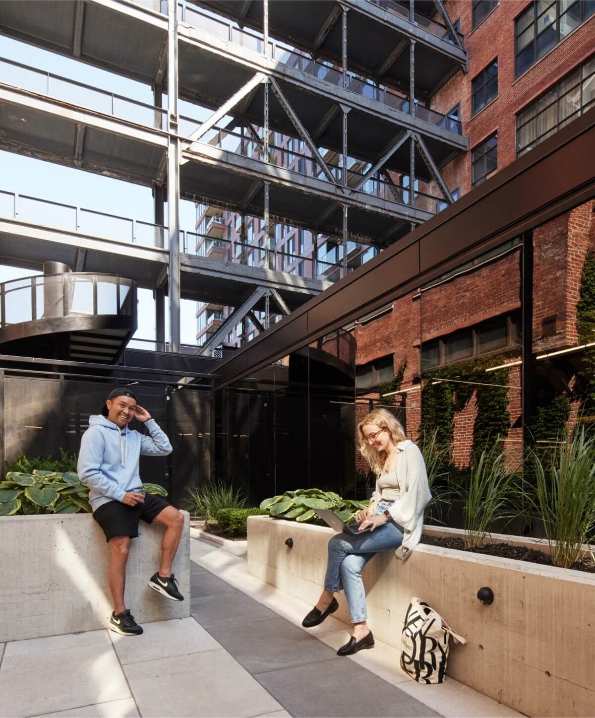 Deux développeurs de logiciels souriants prenant une pause au soleil à l'extérieur du bureau de Workleap