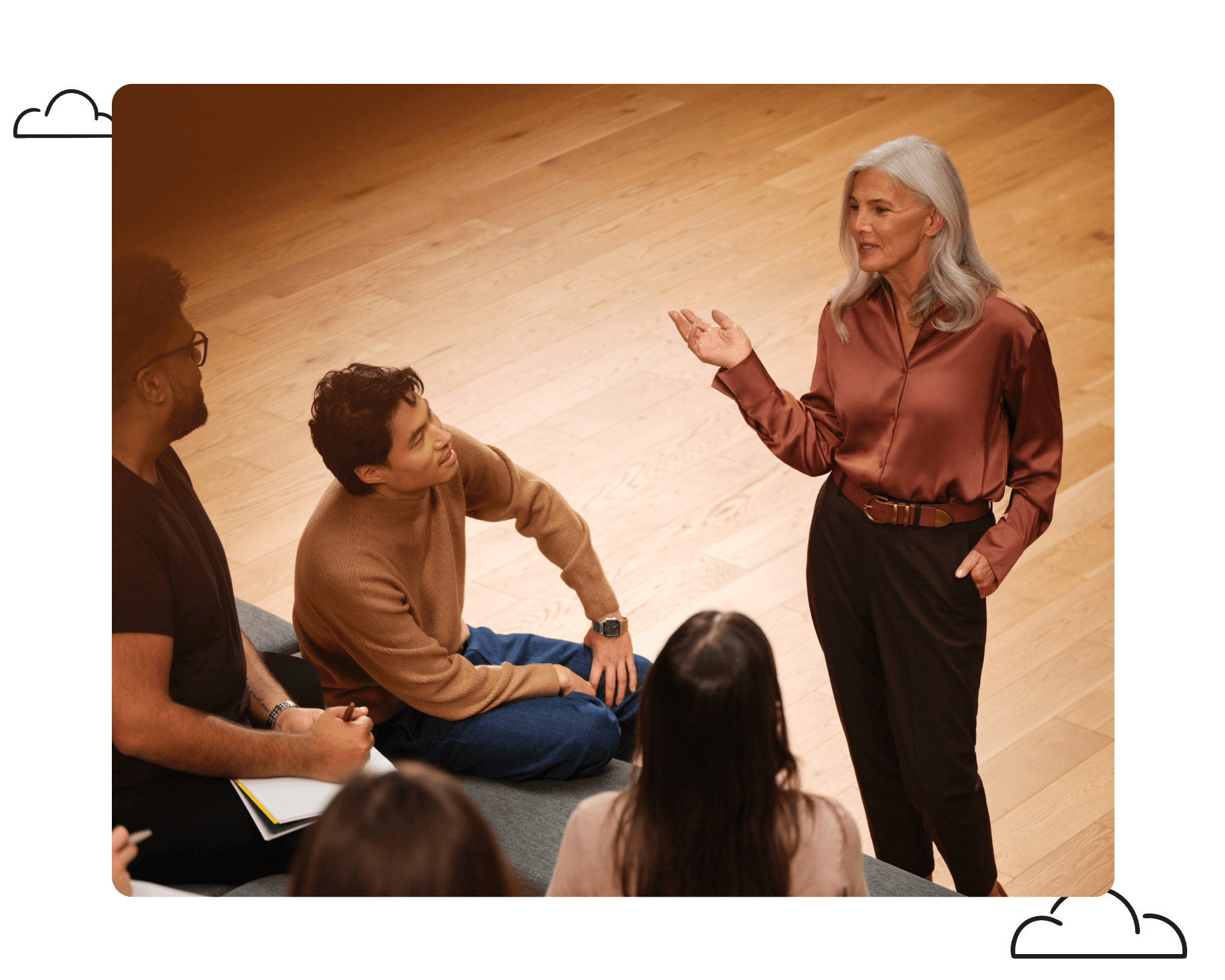 A manager engaged in a conversation with her colleagues in a professional office setting. She stands confidently, leading the discussion while her attentive colleagues